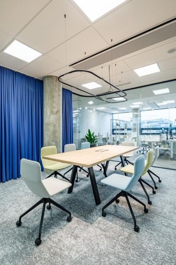 Zasedací místnost s komfortním interiérem a čtvercovým kobercem v odstínech šedé