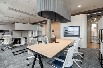 Zóna pro týmová setkání uprostřed open space se zavěšeným akustickým prvkem