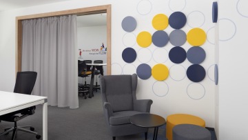 Pohodlné křeslo v rohu s akustickými prvky na zdi pro větší soukromí