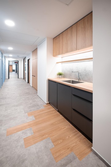 Malá firemní kuchyňka na chodbě v dřevěném dekoru se skvělým osvětlením v kancelářích OHLA ŽS