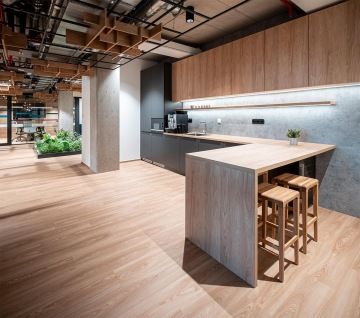 Moderní kuchyňka v dřevěném dekoru s barovým stolkem a židlemi v kancelářích OHLA ŽS