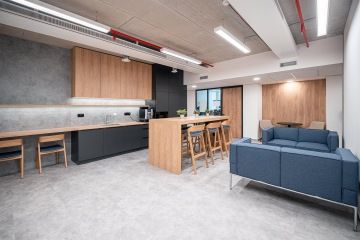 Moderní kuchyňka v dřevěném dekoru s barovým stolkem a židlemi v kancelářích OHLA ŽS