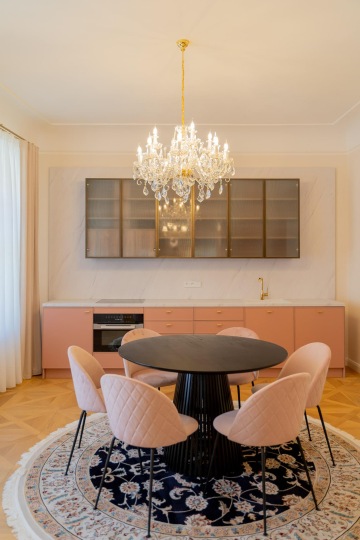 historický lustr v kontrastu s moderním kulatým stolem a čalouněnými křesly