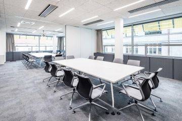 Zasedací místnost v šedých barvách s bílými prvky.