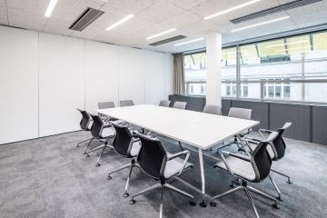 Moderní zasedací místnost v šedo-bílých barvách.