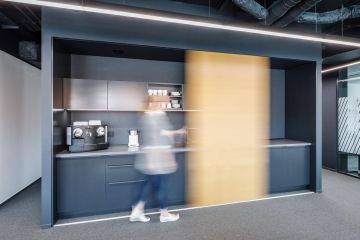 Tmavá pracovní kuchyňka s mobilní dřevěnou příčkou ve společnosti Sev.en Energy.