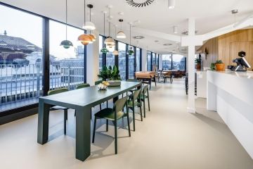 Moderní styl firemní kuchyňky s jídelním stolem a závěsnými lampami v co-workingu Spaces Albatros