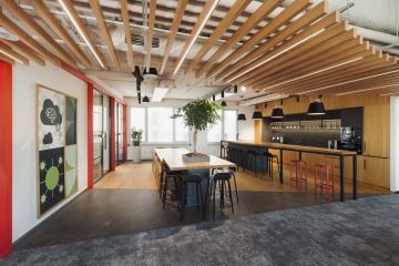 Kancelářská kuchyň s otevřeným prostorem, pracovními plochami a moderním vybavením.