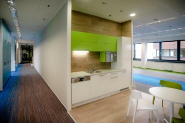 Fit-out pro společnost QBE zahrnuje designově sladěnou kuchyňku se zelenými skříňkami.