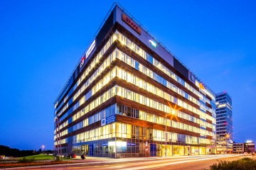 Pohled zvenku na celou budovu Explora Jupiter k večeru, kdy díky osvětlení v jednotlivých patrech vyniká její provedení.