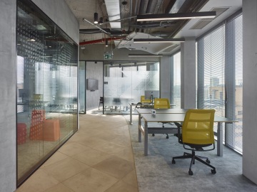 Open space area surrounded by glass-walled meeting rooms