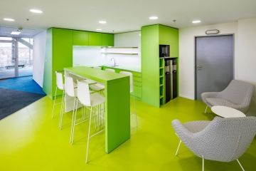 Firemní kuchyňka v zeleném provedení s barovým stolem a židlemi