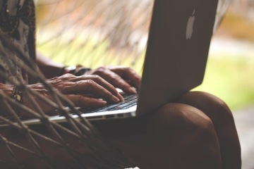 Closeup of a woman sitting in a hammock with a laptop