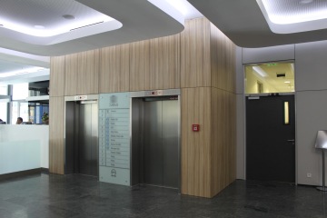 Vstupní interiér budovy CUBUS charakterizuje šedá barva podlahy a dřevěný obklad u výtahů.