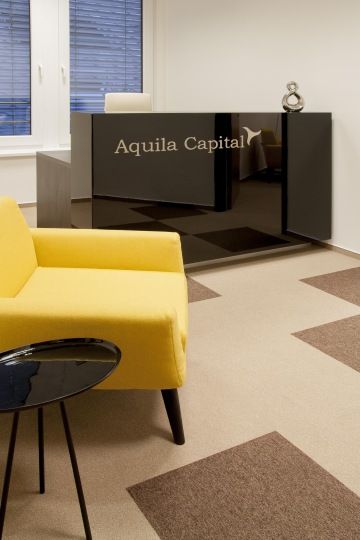Entrance spaces with a custom-made black reception desk with a company logo and a bright yellow armchairs for visitors.