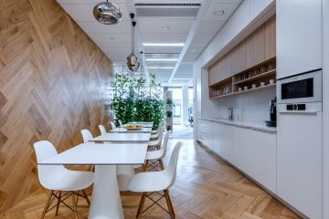 Stylová a svěží kancelářská kuchyňka s bílým nábytkem, dřevěnou podlahou a zelenými rostlinami