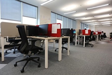 Individual workplaces in a call center are separated by acoustic panels in corporate red color.