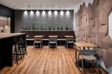 Jídelní stoly obklopené zelenou stěnou a akustickými prvky