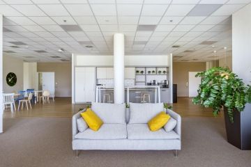 Firemní kuchyňka v bílé barvě a komfortní křeslo pro odpočinek