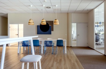 Prostředí firemní kuchyňky s jídelními stoly a židlemi