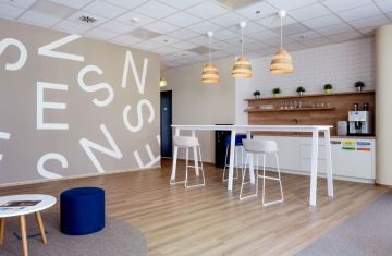 Firemní kuchyňka v bílém provedení s dřevěným dekorem v kancelářích NESS