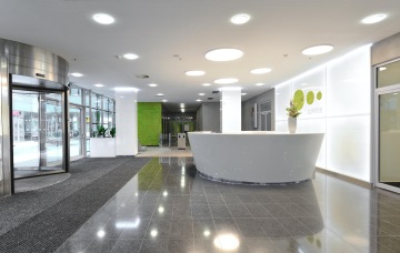 Revitalizace hlavního vstupního prostoru dominuje bílou recepcí v budově Explora Business Centrum. Velká kulatá světla na stropě dodávají prostoru eleganci.