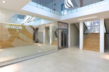 The entrance hall is optically extended using a mirror wall with ornaments created from the company name, and thanks to the open view of the first floor, the whole hall is very spacious.