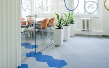 Pohled na skleněné oddělení s firemními polepy rozdělující openspace kanceláře a zasedací místnost.