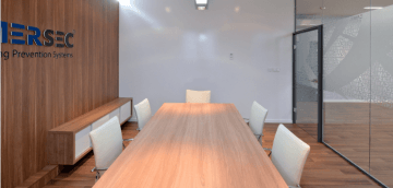 The Amersec meeting room is built in a combination of walls and armchairs in white colour, a wooden table and walls with a storage space, and the whole room is separated from the corridor by a glass partition.